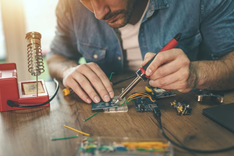 Technicien effectuant un test sur un circuit imprimé dans un atelier de réparation informatique.